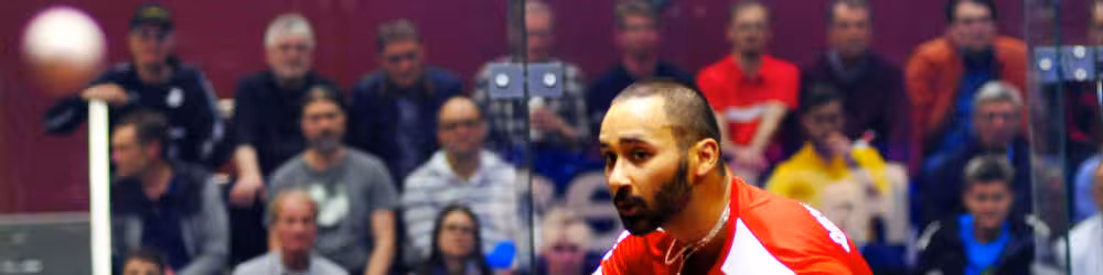 A professional squash player focusing on the ball